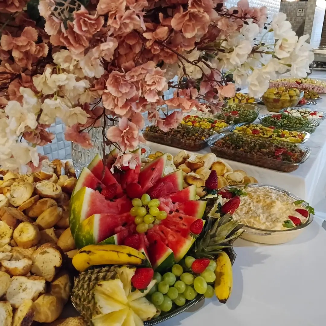 Mesa de evento com frutas, pães e uma variedade de entradas preparadas pela Bom a Bessa